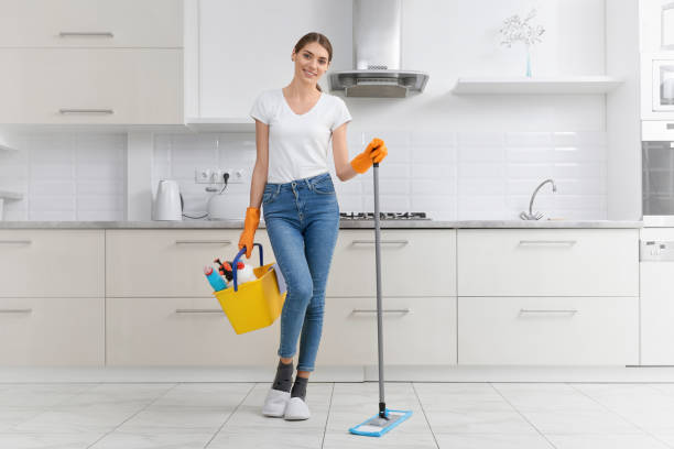 Beautiful young woman standing with mop and detergent and preparing for cleaning. Concept of cleaning in kitchen.